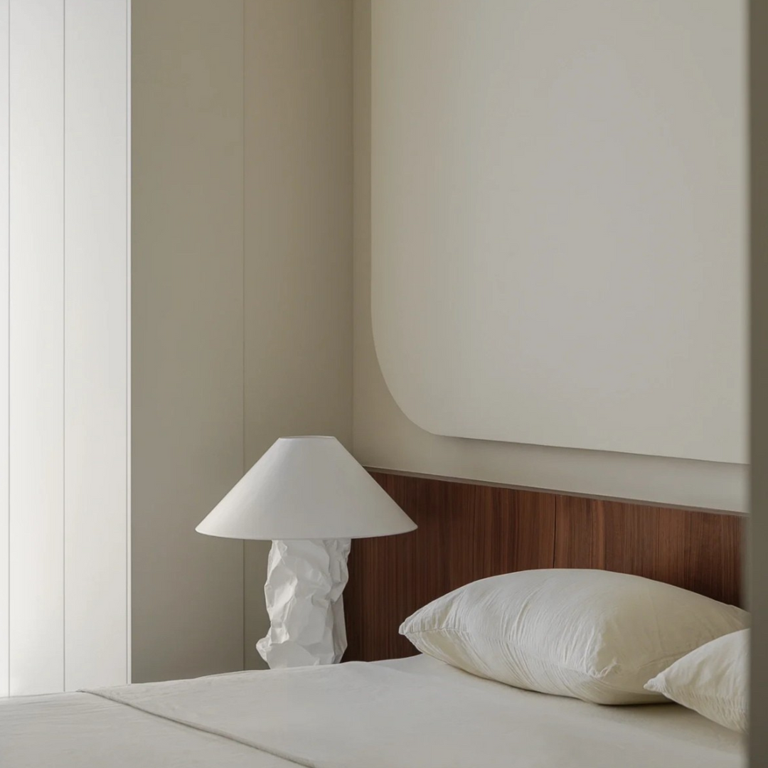 Wabi-sabi style table lamp on wood-accented bed setting.