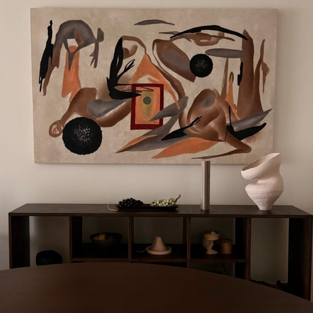 Wabi-sabi vase styled below abstract wall art in neutral tones.