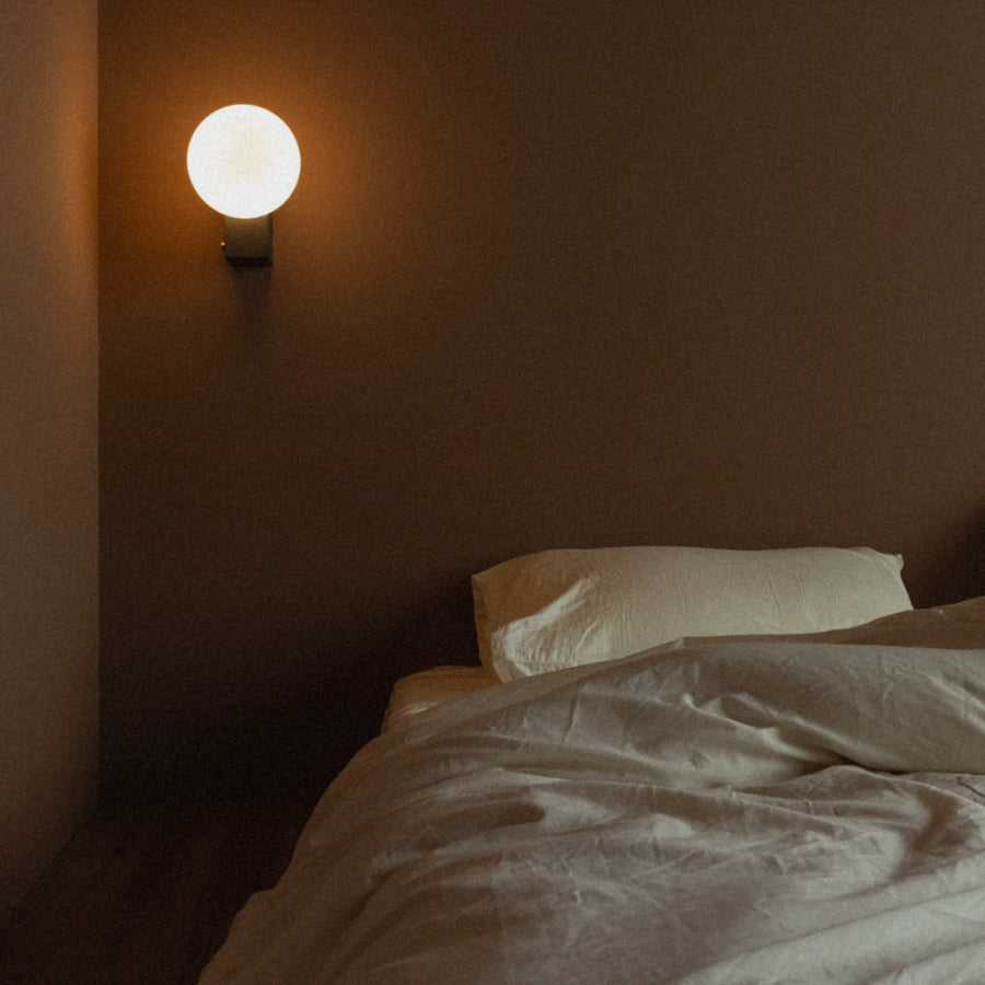 globe wall lamp casting a soft glow across the wall in a bedroom setting.
