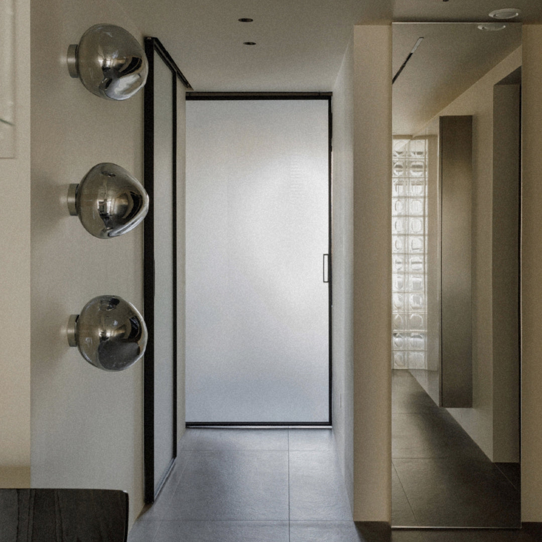glass wall sconce arranged vertically in a hallway near a doorway.