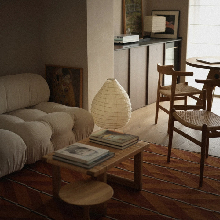 washi paper lantern floor lamp placed beside a sofa and coffee table adding soft diffused lighting to a modern living room.