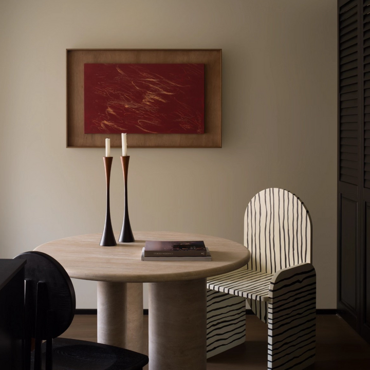 Tall wooden candle holders with black-to-brown tones styled on a sculptural table in a Japandi living room.