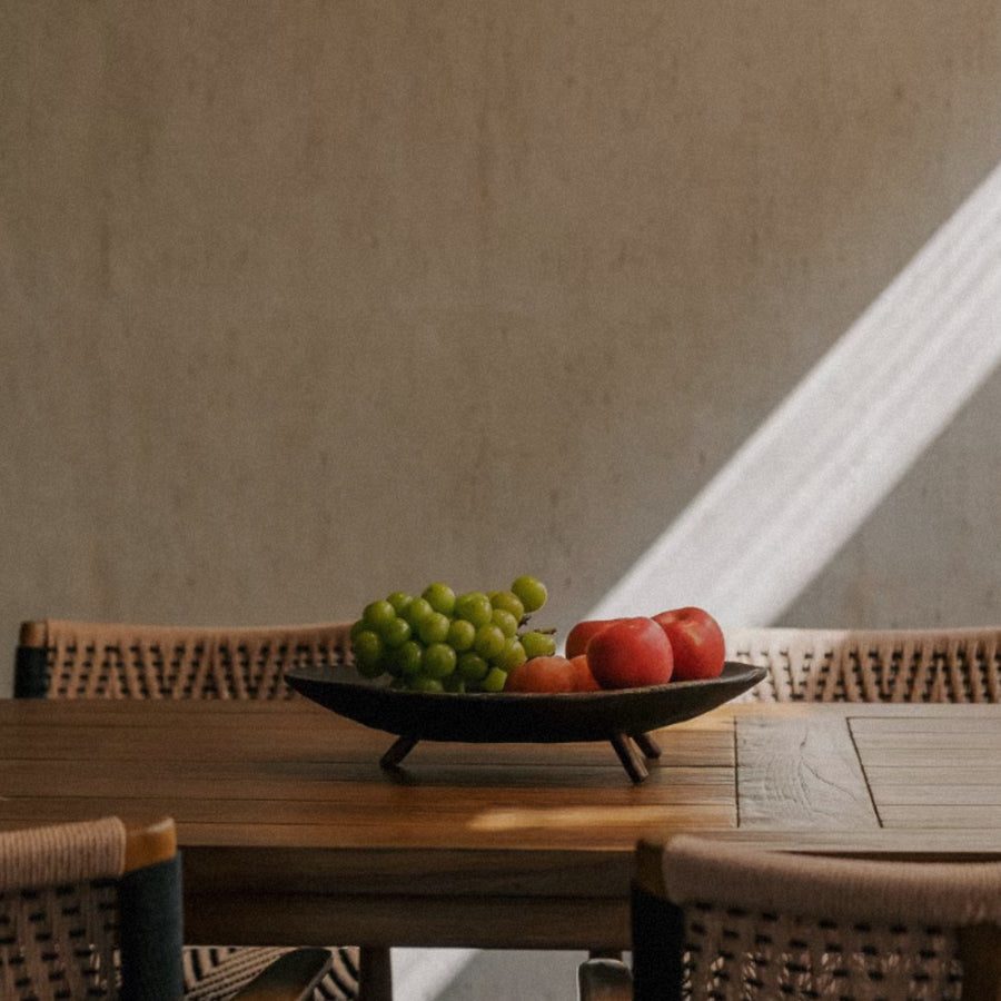 wood fruit bowl placed on a dining table holding mixed fruit in natural light.