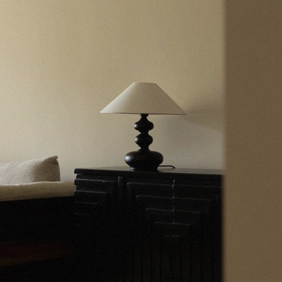 wooden table lamp set on a dark sideboard adding soft ambient light.