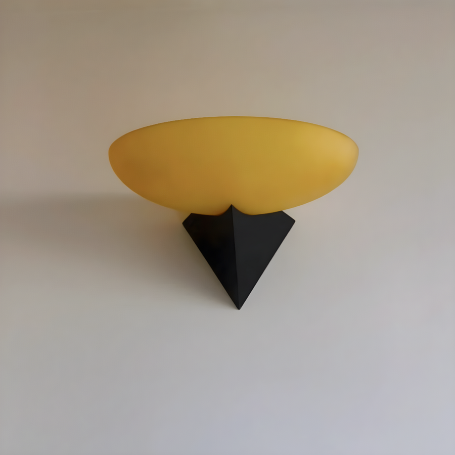 Close-up of a yellow wall lamp with a distinctive black base, highlighting its unique design and vibrant color.